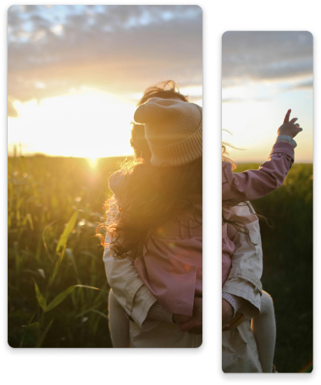 A young girl on someone's shoulders, pointing toward the sunset.