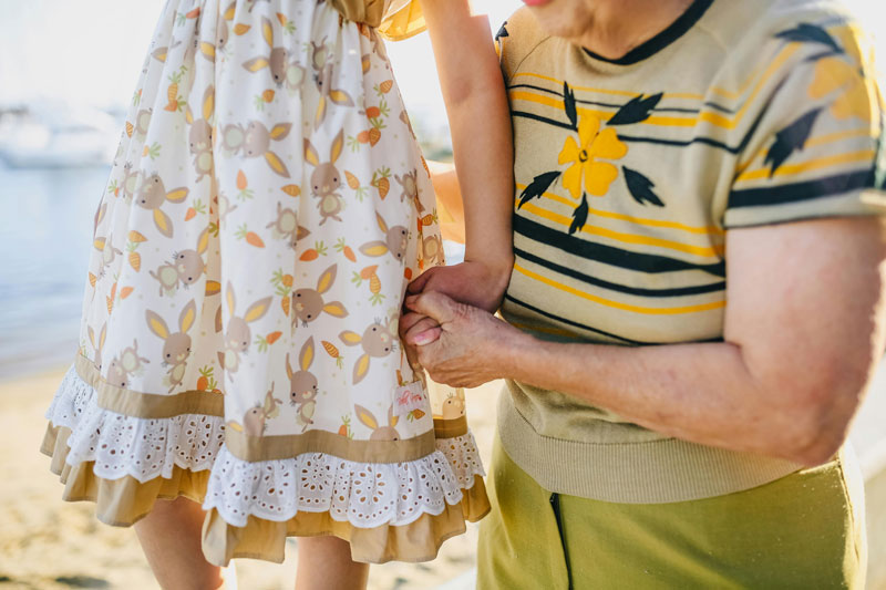 Older woman holding hands with a child wearing a dress with bunny patterns.