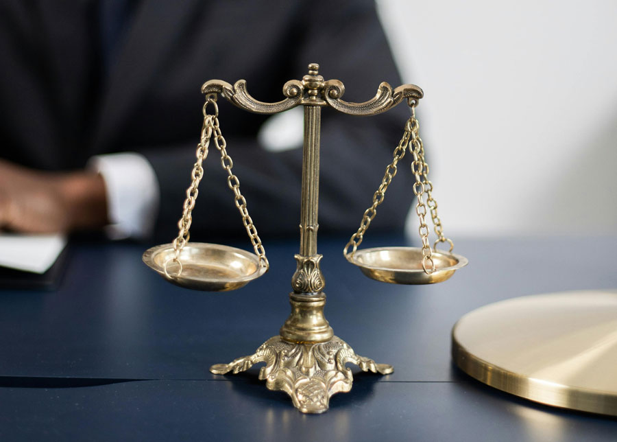 Golden scales of justice on a table in front of a person.