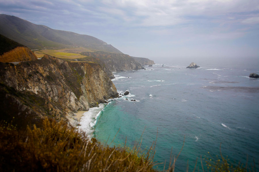 Cliffside view of the ocean with rugged coastline and misty sky.